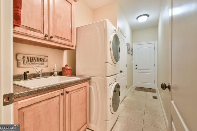 laundry room featuring cabinets, light tile patterned floors, stacked washer / drying machine, and sink