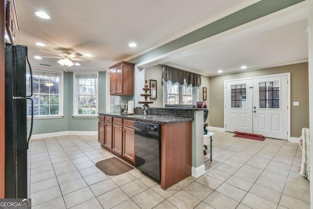 kitchen with ceiling fan, dark stone countertops, crown molding, light tile patterned floors, and black appliances