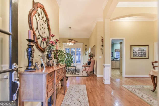 foyer entrance featuring sink, crown molding, light hardwood / wood-style flooring, ceiling fan, and ornate columns