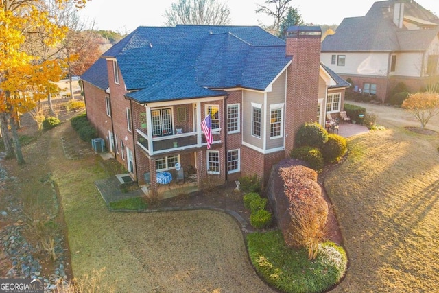 view of front of property featuring central air condition unit, a balcony, and a front yard