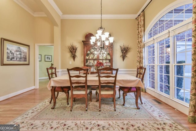 dining space featuring ornamental molding, light wood-type flooring, and a notable chandelier