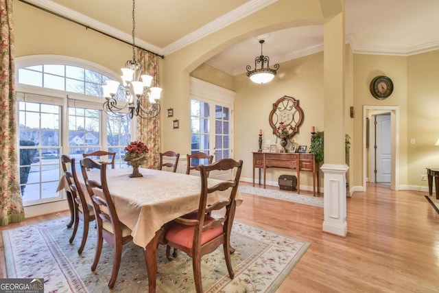 dining area featuring ornamental molding, light hardwood / wood-style floors, decorative columns, and a notable chandelier