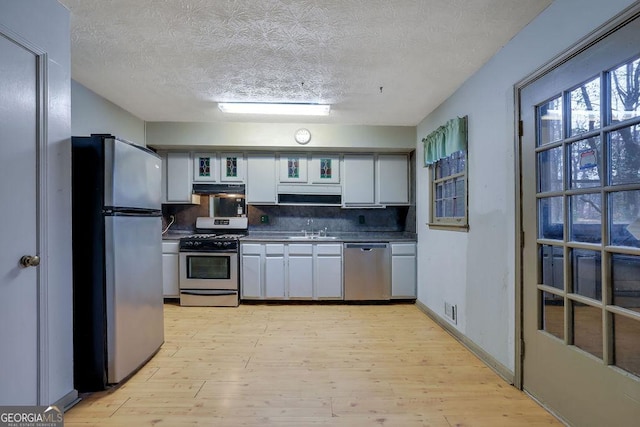 kitchen with sink, white cabinets, backsplash, stainless steel appliances, and a textured ceiling