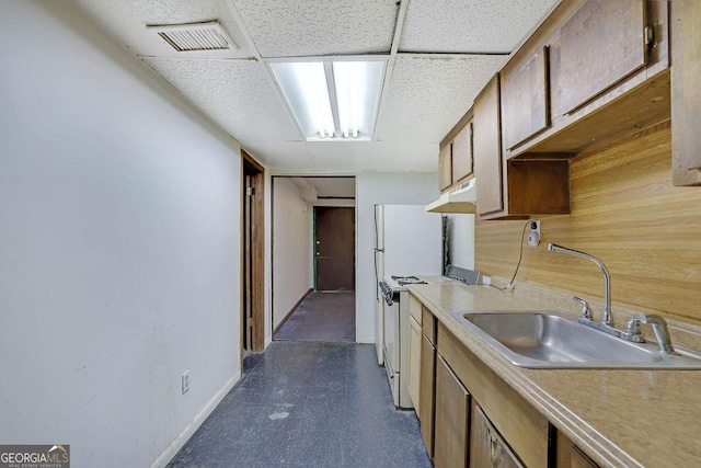 kitchen with sink, wooden walls, white gas stove, and a paneled ceiling