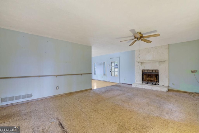 unfurnished living room with ceiling fan, light colored carpet, and a fireplace