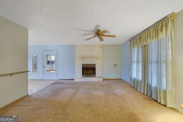 unfurnished living room with ceiling fan, a large fireplace, and light colored carpet