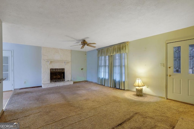 unfurnished living room with ceiling fan, light colored carpet, a fireplace, and a textured ceiling