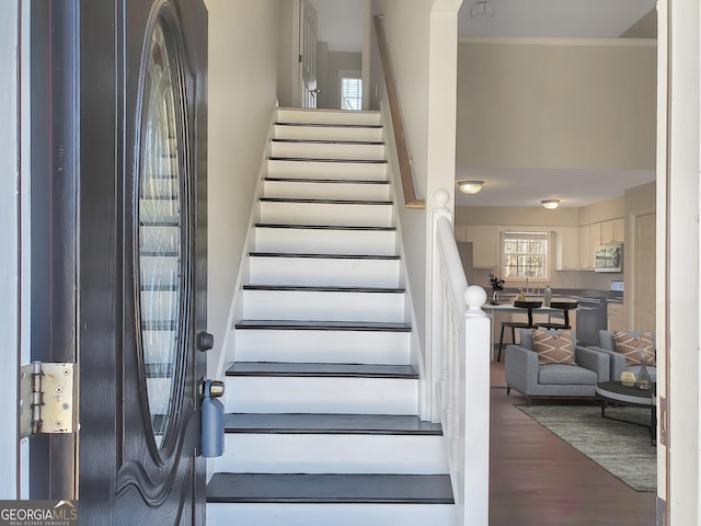 stairway featuring wood finished floors and ornamental molding