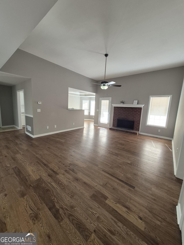 unfurnished living room featuring ceiling fan, dark hardwood / wood-style flooring, and a brick fireplace