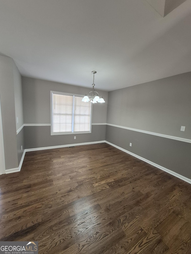 unfurnished dining area with dark hardwood / wood-style floors and a chandelier