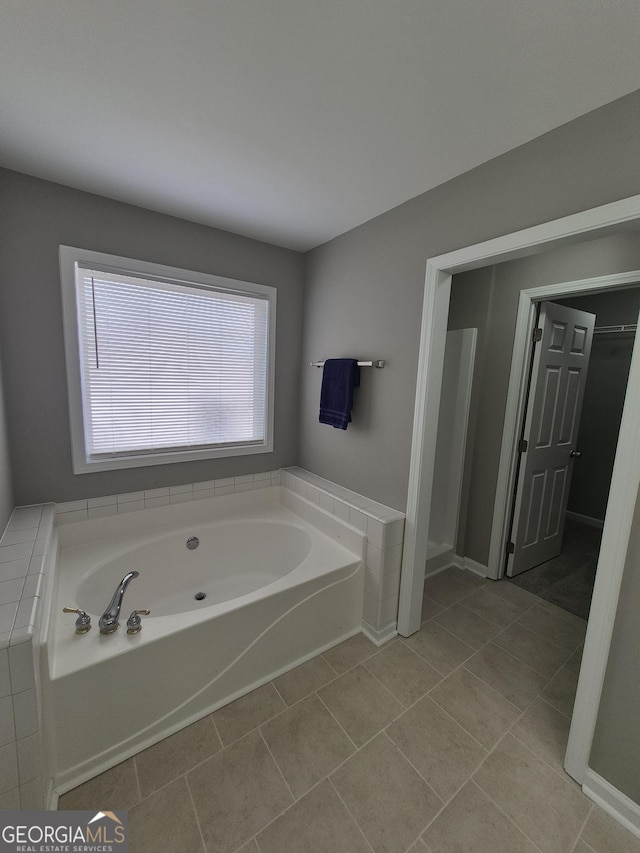 bathroom with tile patterned flooring and a tub to relax in