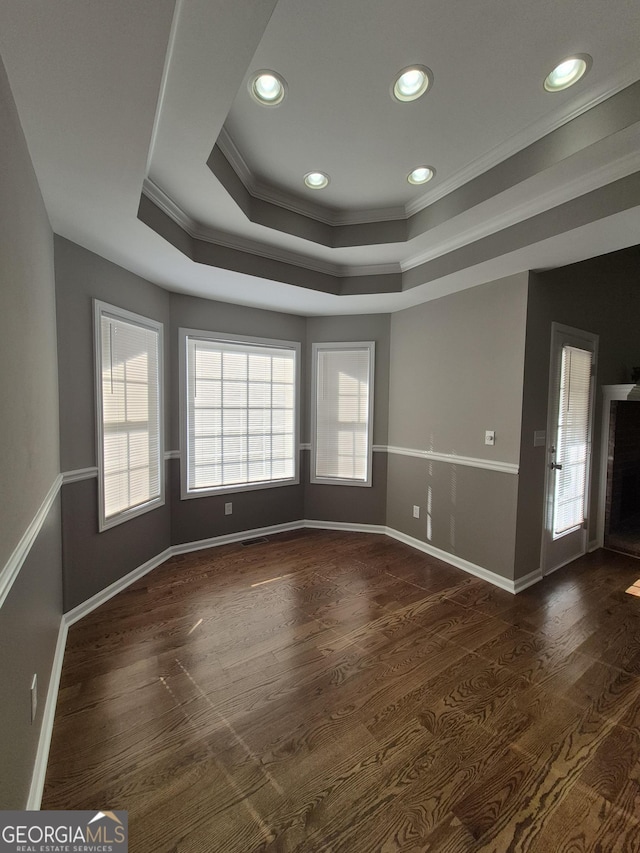 spare room with dark hardwood / wood-style floors, a raised ceiling, and crown molding