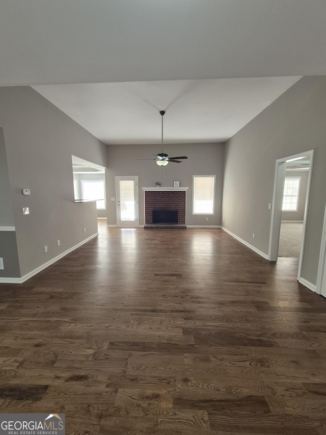 unfurnished living room featuring ceiling fan, dark hardwood / wood-style flooring, and a brick fireplace