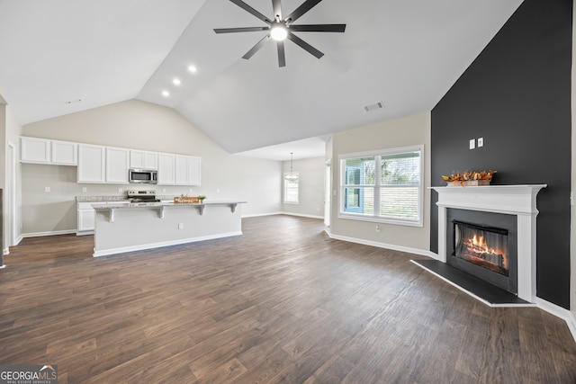 unfurnished living room with ceiling fan, dark wood-type flooring, and vaulted ceiling