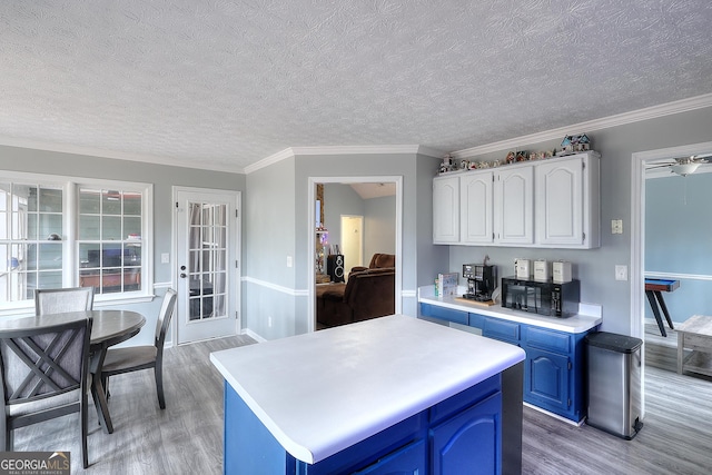 kitchen with black microwave, light countertops, light wood-type flooring, and blue cabinets