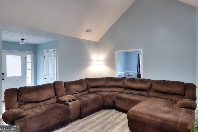 living room with high vaulted ceiling, visible vents, and light wood-style flooring