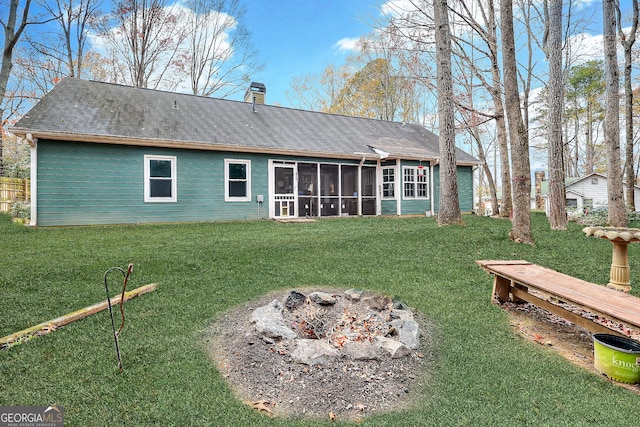 back of property featuring a fire pit, a sunroom, and a lawn