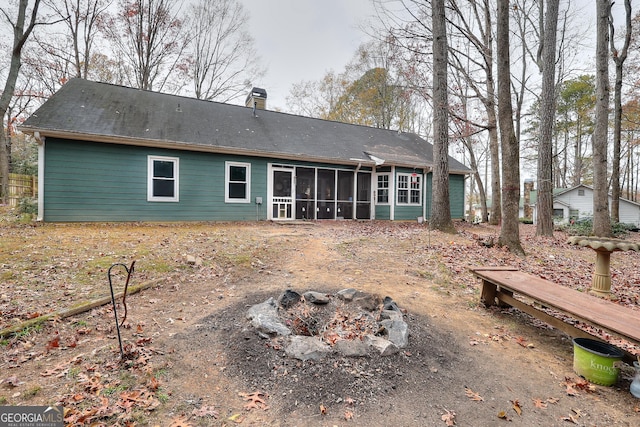 rear view of house featuring a fire pit, a sunroom, and a chimney