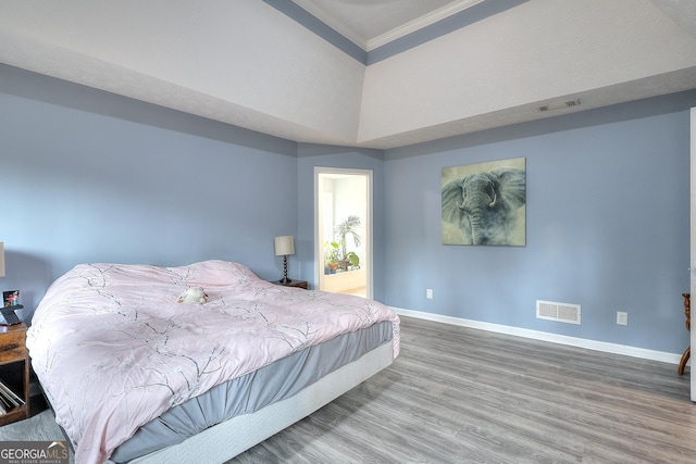 bedroom featuring ornamental molding, wood finished floors, visible vents, and baseboards