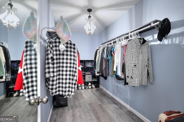 walk in closet with a chandelier and wood finished floors