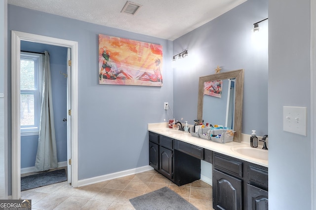 full bathroom featuring double vanity, visible vents, tile patterned floors, a textured ceiling, and a sink