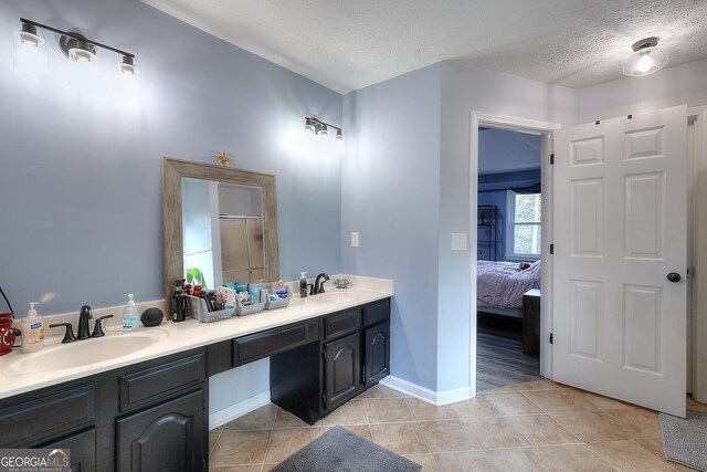 bathroom with tile patterned flooring, vanity, a shower with door, and a textured ceiling