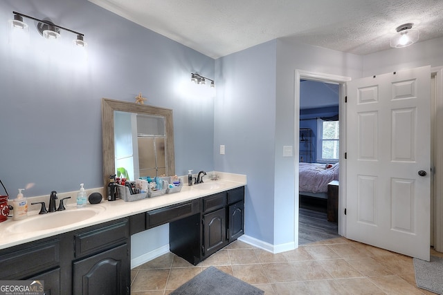 bathroom with a textured ceiling, double vanity, a sink, and tile patterned floors