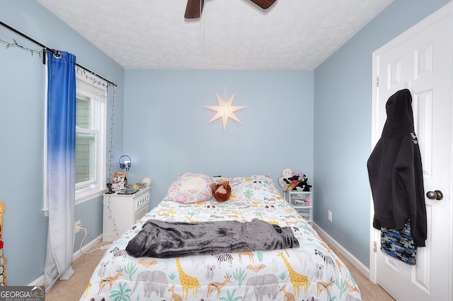 bedroom with ceiling fan, light carpet, and a textured ceiling