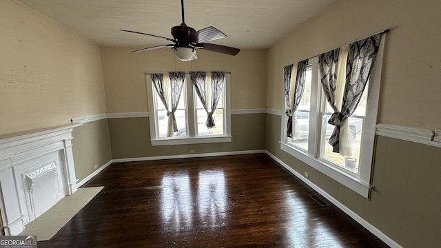 unfurnished living room with plenty of natural light, dark hardwood / wood-style floors, and ceiling fan