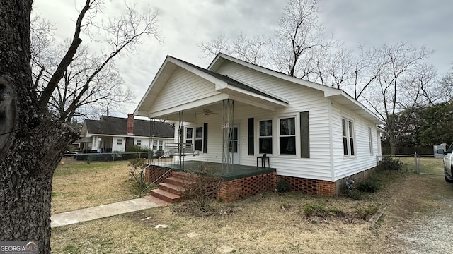 bungalow-style house featuring ceiling fan, a front lawn, and covered porch