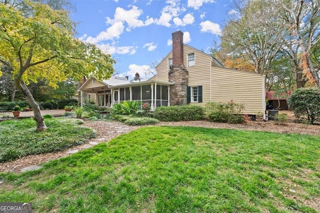 rear view of house with a sunroom and a yard