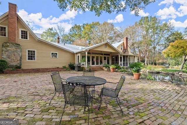 view of patio / terrace featuring a sunroom, a grill, and french doors