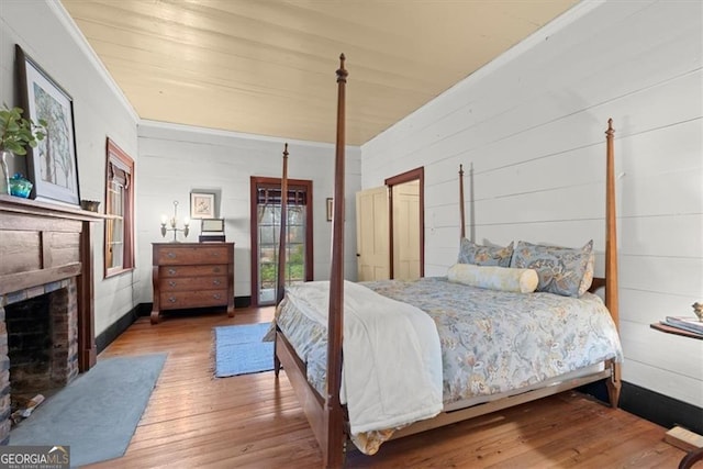 bedroom featuring a brick fireplace, crown molding, and hardwood / wood-style flooring