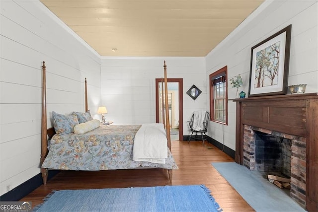 bedroom featuring dark hardwood / wood-style flooring and a brick fireplace