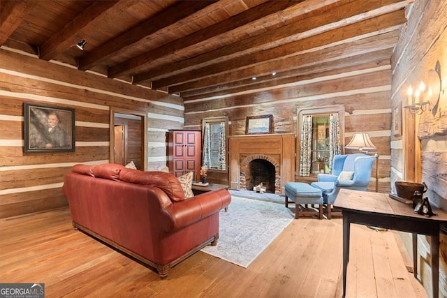 interior space featuring wood walls, wooden ceiling, a brick fireplace, light hardwood / wood-style floors, and beam ceiling