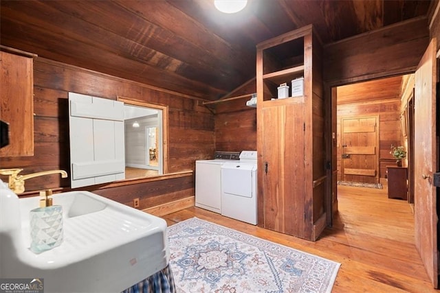 washroom featuring wood walls, sink, light hardwood / wood-style flooring, and independent washer and dryer