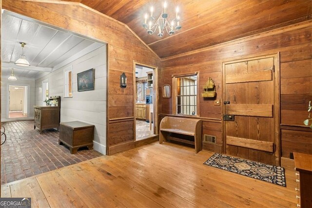 foyer entrance with hardwood / wood-style floors, wooden walls, wooden ceiling, and lofted ceiling