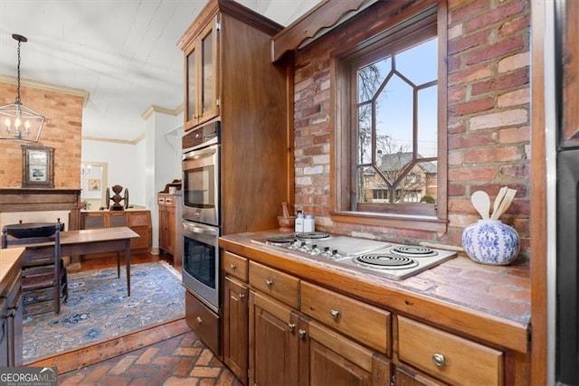 kitchen with brick wall, stainless steel appliances, crown molding, a chandelier, and hanging light fixtures