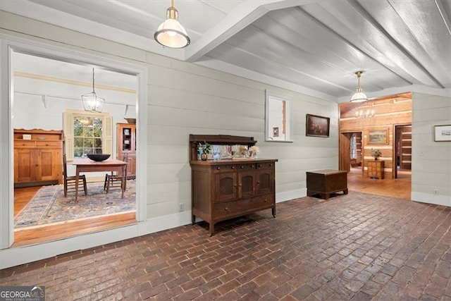 interior space featuring wood walls, beam ceiling, and a chandelier