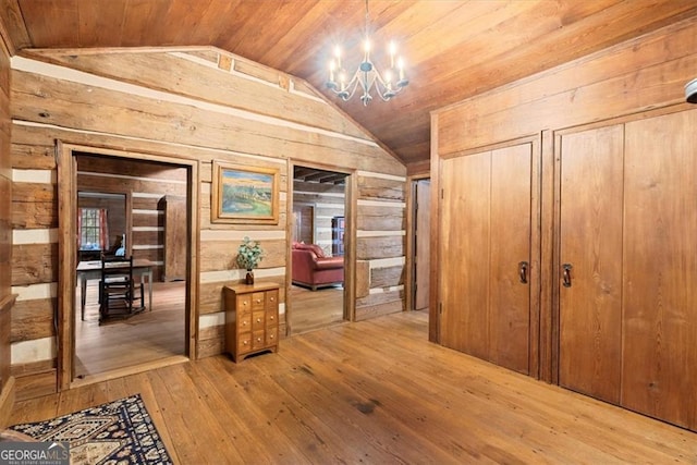 hall featuring a chandelier, vaulted ceiling, wood-type flooring, wooden walls, and wood ceiling