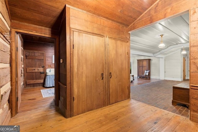 corridor with wood walls, wood ceiling, lofted ceiling, and hardwood / wood-style flooring