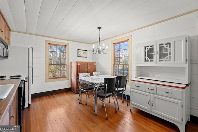 dining space featuring light hardwood / wood-style flooring, a wealth of natural light, and a notable chandelier