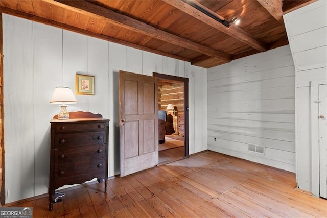 unfurnished bedroom featuring beamed ceiling, light hardwood / wood-style flooring, wood walls, and wood ceiling