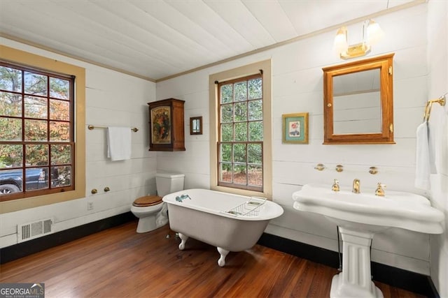 bathroom featuring hardwood / wood-style floors, crown molding, toilet, and a bath