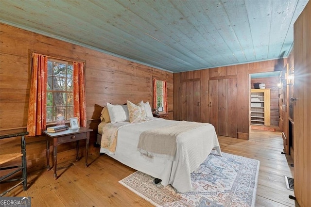 bedroom featuring wooden ceiling, light hardwood / wood-style floors, and wooden walls