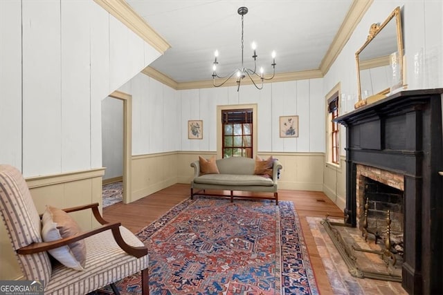 living area featuring light hardwood / wood-style floors, ornamental molding, and an inviting chandelier