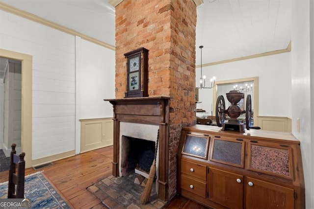 interior space featuring a notable chandelier, dark hardwood / wood-style floors, ornamental molding, and a fireplace