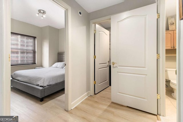 bedroom featuring ensuite bath and light hardwood / wood-style flooring