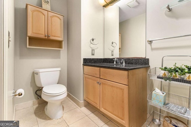 bathroom with toilet, vanity, and tile patterned floors