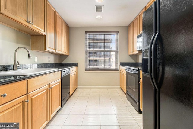 kitchen featuring dark stone countertops, sink, light tile patterned floors, and black appliances